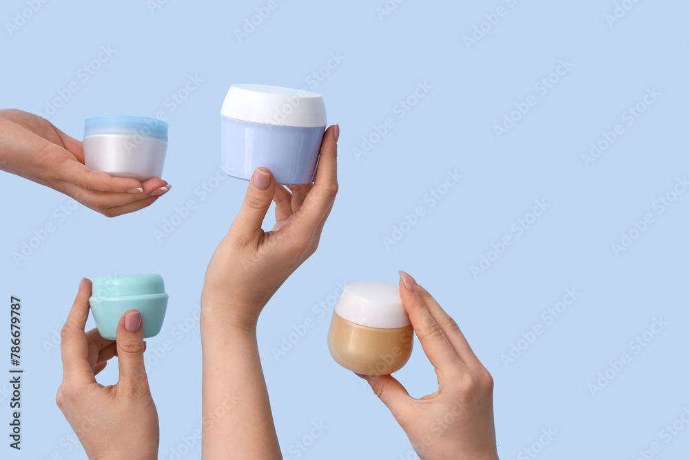 Women with jars of hand cream on blue background Women with jars of hand cream on blue background