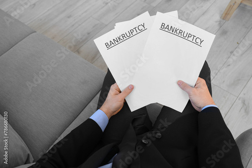 Bankrupt businessman with papers sitting in office, closeup
