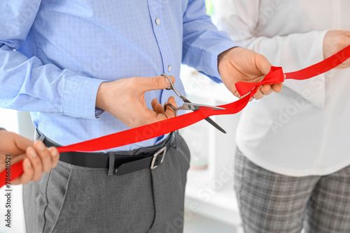 Business man cutting red ribbon in office, closeup © Pixel-Shot