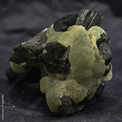 This captivating specimen features prehnite's botryoidal texture and glowing green hue, accented by dark mineral inclusions photo