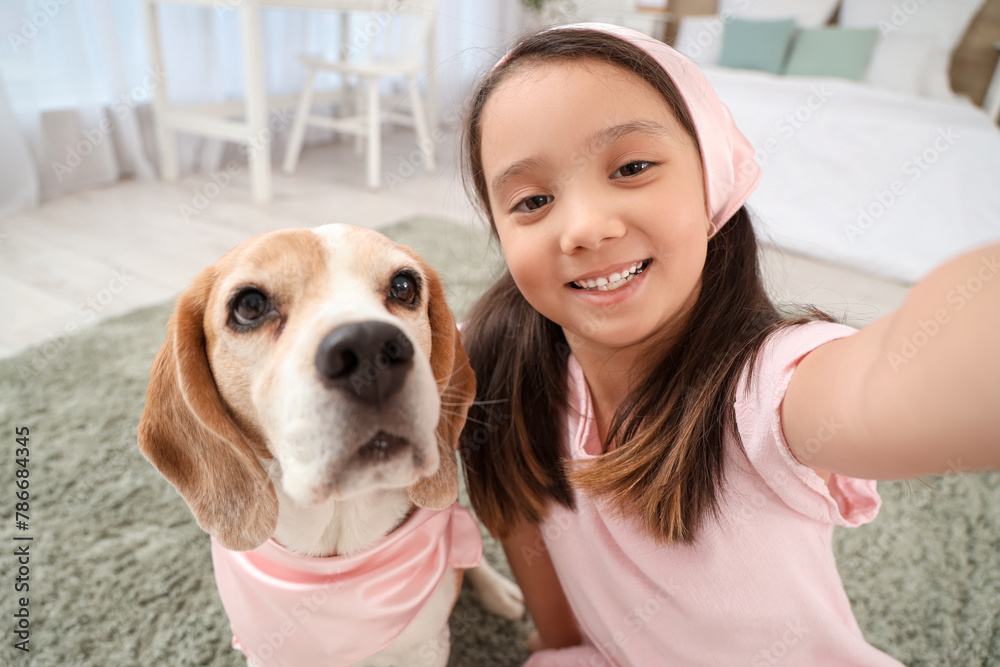 Cute little Asian girl and Beagle dog with pink scarves taking selfie in bedroom, closeup Cute little Asian girl and Beagle dog with pink scarves taking selfie in bedroom, closeup