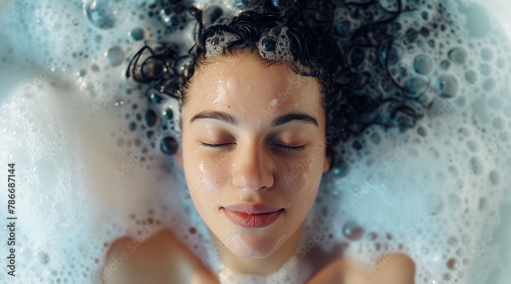 A top down view of a woman relaxing in a bubble bath. Closeup candid portrait