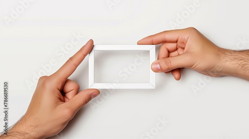 Two hands holding an empty white picture frame on a clean background, ideal for photo framing, design templates, and creative mockups