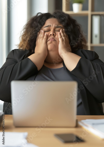 Exhausted tired plus sized office worker, woman sitting at desk, looking tired, eyes closed, hands on her head. Generative AI