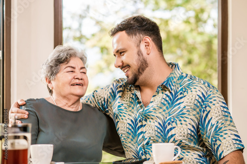 Portrait of an older adult with his son hugging each other celebrating Mother's Day.