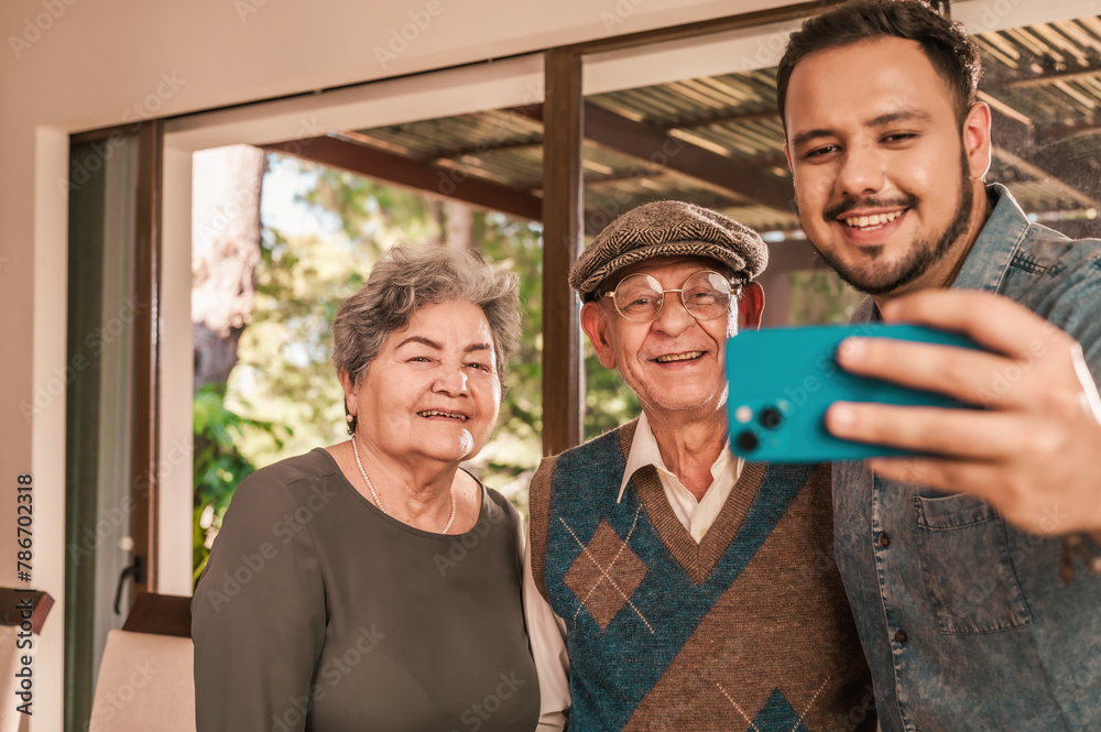 Hispanic Family Making Selfie On Smartphone Posing. Son with his old father and mother.
