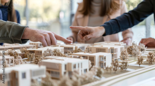 Close-up of a professional team pointing and discussing details on an architectural scale model during a project review meeting. 