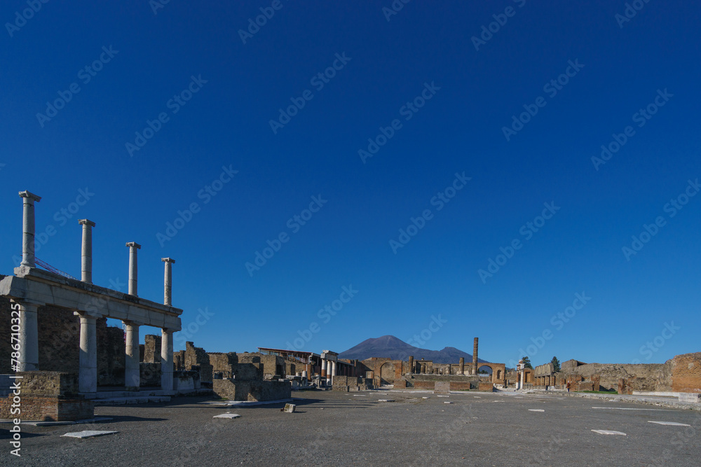 View of Mount Vesuvius through the ruins of the Forum on a sunny day with clear blue sky, Pompeii, Campania, Italy