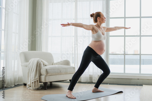Fototapeta Naklejka Na Ścianę i Meble -  Pregnancy yoga fitness workout training. Pregnant woman practicing yoga at home. Pregnant girl doing sports exercise on yoga mat indoor. Woman with big belly have fitness training practicing asana