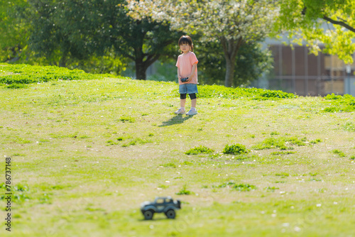 芝生の公園でラジコンで遊ぶ子ども