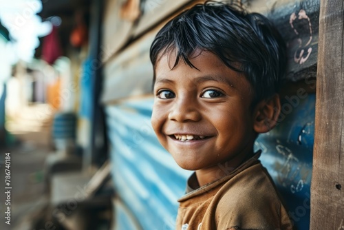 Portrait of a little boy smiling at the camera. The child is wearing brown clothes.