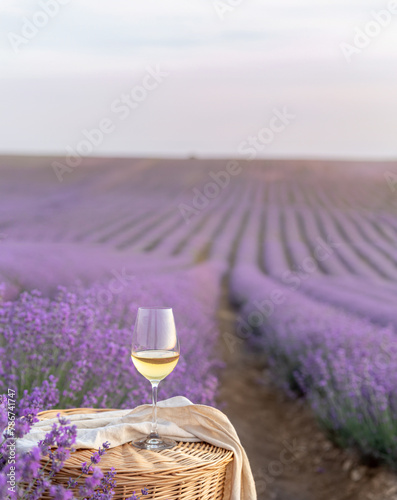Glass of white wine in a lavender field. Violet flowers on the background.