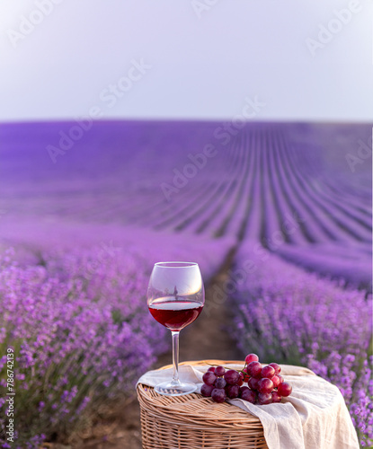 Glass of white wine in a lavender field. Violet flowers on the background. © Kotkoa