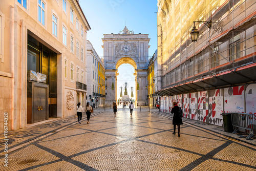 Pedestrians walk on the decorated Portuguese Pavement calçada near the historic Arco da Rua Agusta arch on Praça do Comércio square in the Baixa city center district of Lisbon, Portugal.  photo