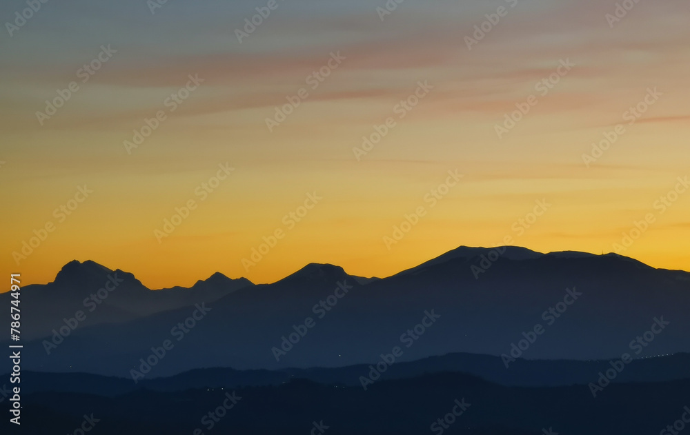 Le montagne in controluce in un luminoso tramonto arancione
