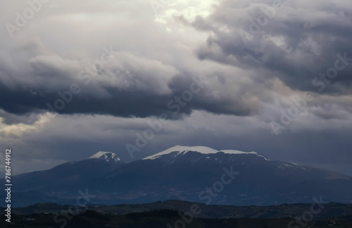 Montagne innevate in inverno e cielo coperto di grandi nuvole grigie © GjGj