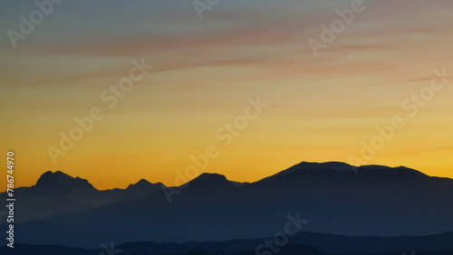 Le montagne in controluce in un luminoso tramonto arancione photo