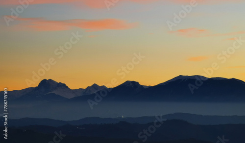 Le montagne in controluce in un luminoso tramonto arancione © GjGj