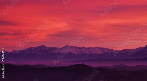 Tramonto rosso fuoco sulle montagne innevate photo