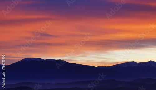 Nuvole rosse al tramonto sulla cime delle montagne © GjGj