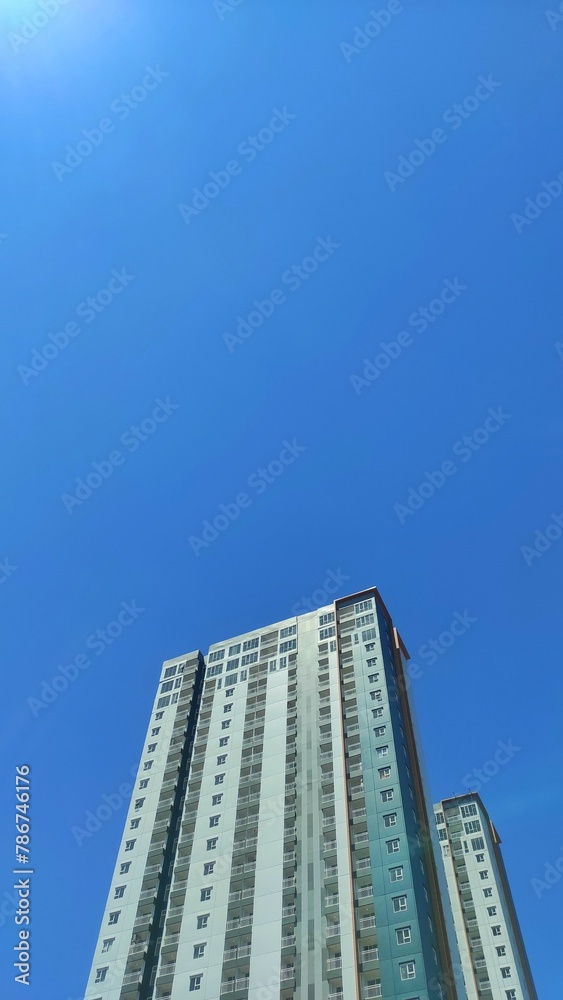A high apartment building in urban area under blue sky during sunny day A high apartment building in urban area under blue sky during sunny day