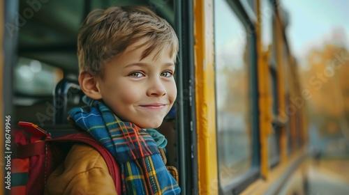 A young boy smiles as he looks out the window of a school bus.