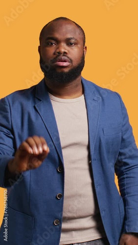 Vertical video Stern african american man doing stop hand gesture sign. Annoyed BIPOC person doing firm halt sign gesturing, wishing to end concept, isolated over studio background, camera B photo