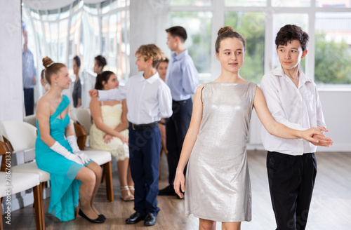 Group of young couple of teenagers in evening dresses dance an polonaise dance