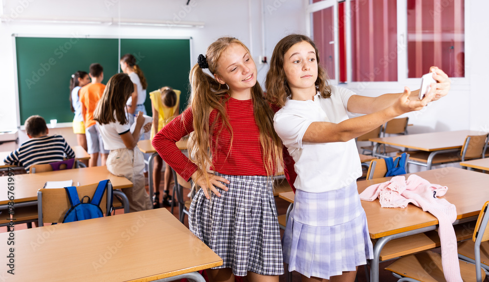 Obraz premium Two positive schoolgirls are photographed during a break in the school class