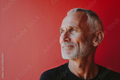 Portrait of an elderly man on a red background. Copy space.