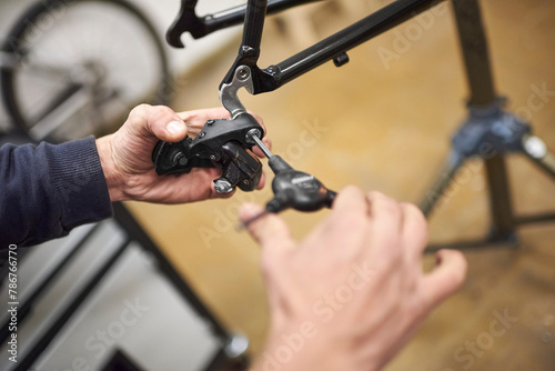 Unrecognizable man assembling the brake system of a bicycle as part of the maintenance service he performs in his workshop. Real people at work. © Carolina Jaramillo