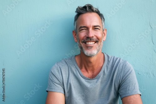 Portrait of handsome Persian man with grey hair smiling against blue background photo