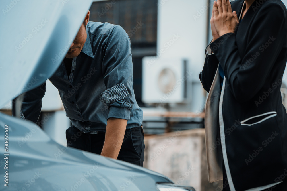 Man help woman fix the car problem. He pop up the car hood to repair the damaged part. uds