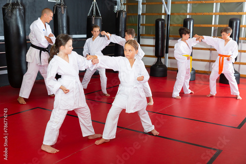 Serious pair of little girls practicing new taekwondo moves during class