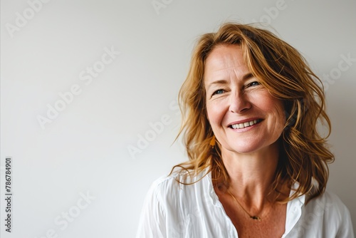Portrait of smiling middle aged woman in white shirt against white background
