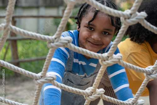 Close up, African child boy climbing a rope ladder and smile at the camera photo