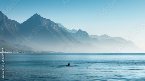 Man swimming in the ocean with a mountain backdrop. Serene aquatic adventure amidst majestic natural scenery