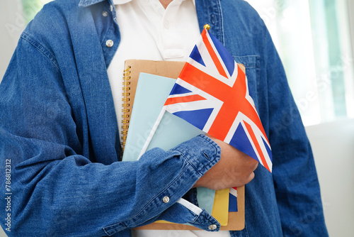 Learning English, Asian teenage student holding book with flag for language program education.