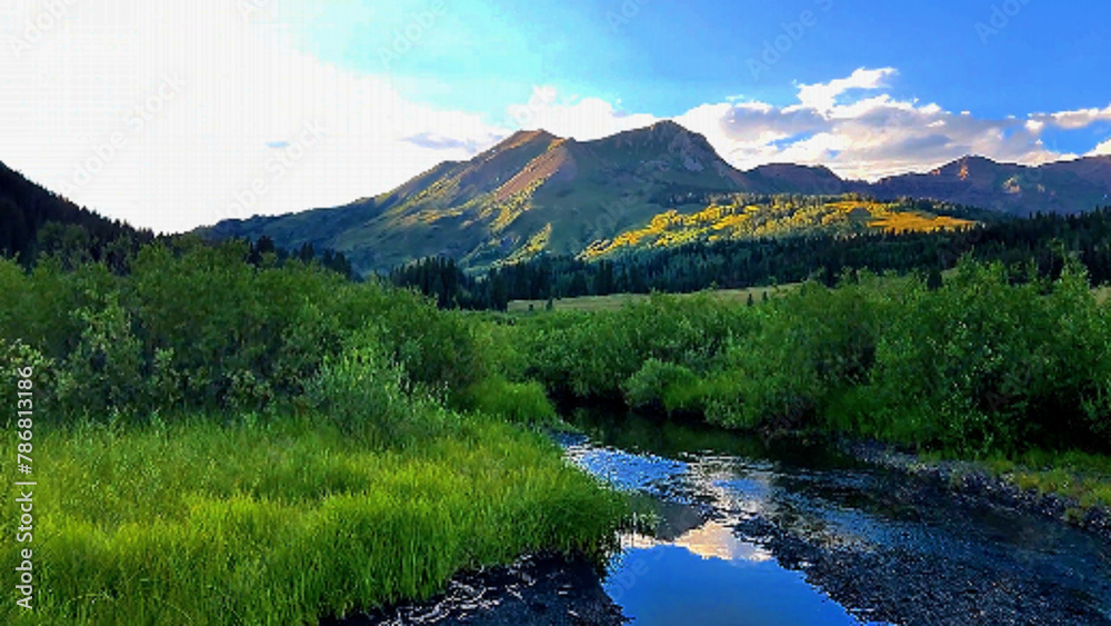Fototapeta premium Sunset in an alpine meadow surrounded by forest and mountain peaks, near Crested Butte, Colorado.