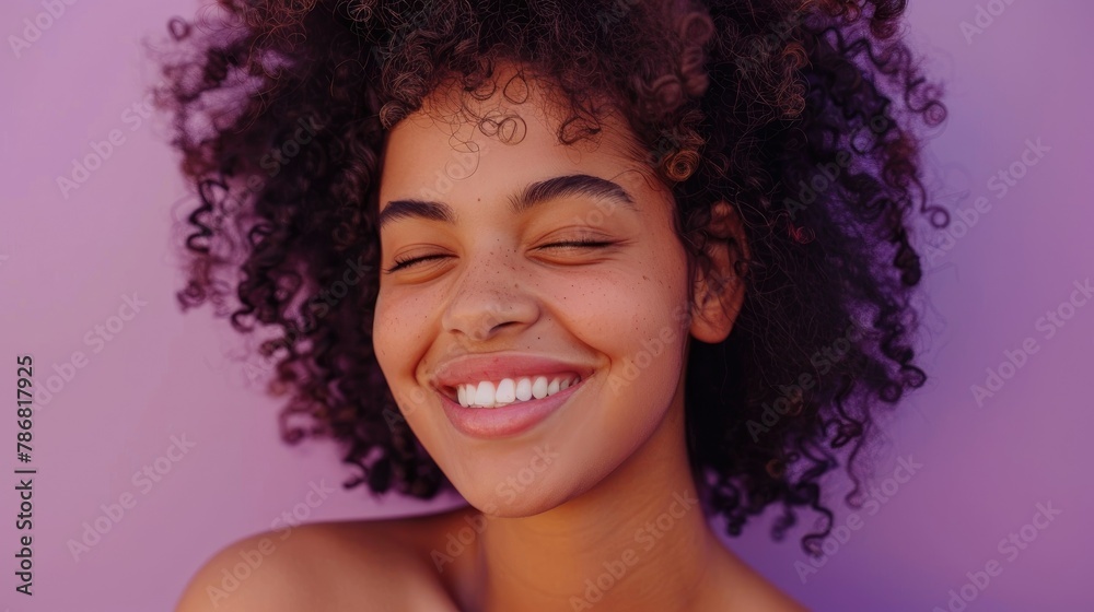 Relaxed curly girl winking smiling and showing approval on a purple background Relaxed curly girl winking smiling and showing approval on a purple background