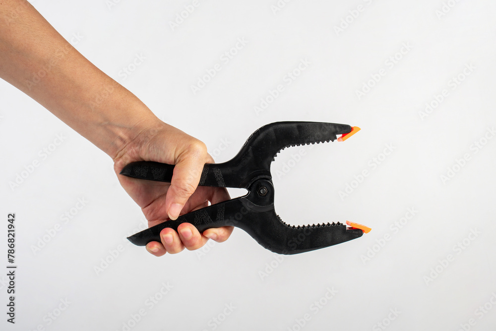 Obraz premium Black plastic spring clamp in hand isolated on white background