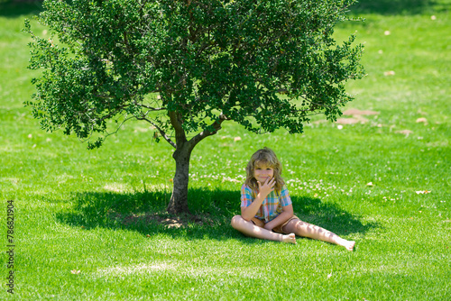 Kid relaxing on green meadow. Child go for a walk in the park. Summer holiday activitie. Kid boy are relaxing outdoor. Child playing in the garden.