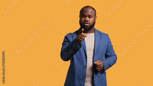 Disappointed african american man admonishing friend over debacle, isolated over studio background. Upset BIPOC person in disagreement with mate, pointing finger and lecturing him, camera B photo
