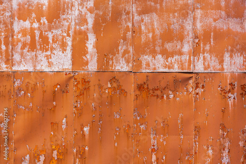 bright orange paint of rusty metal wall. industrial background with peeling paint texture.