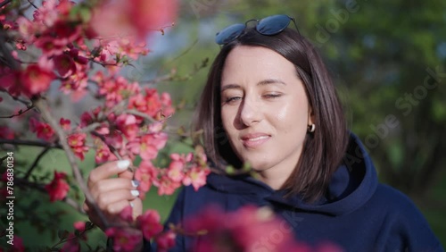 Woman smell blooming Chinese Quince shrub, outdoor park recreation, Prague photo