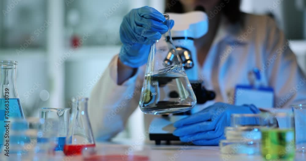 Scientist moves glass container with transparent substance
