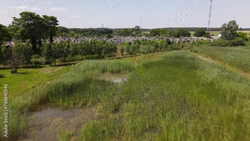 Rising aerial flyover above swampy wetlands towards cemetery, Batya, Hungary. photo