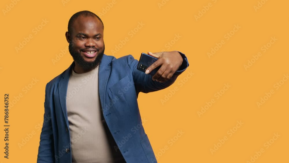 African american narcissistic man using cellphone to take selfies from all angles. Vain social media user taking photos using phone selfie camera, smiling happily, studio background, camera B African american narcissistic man using cellphone to take selfies from all angles. Vain social media user taking photos using phone selfie camera, smiling happily, studio background, camera B