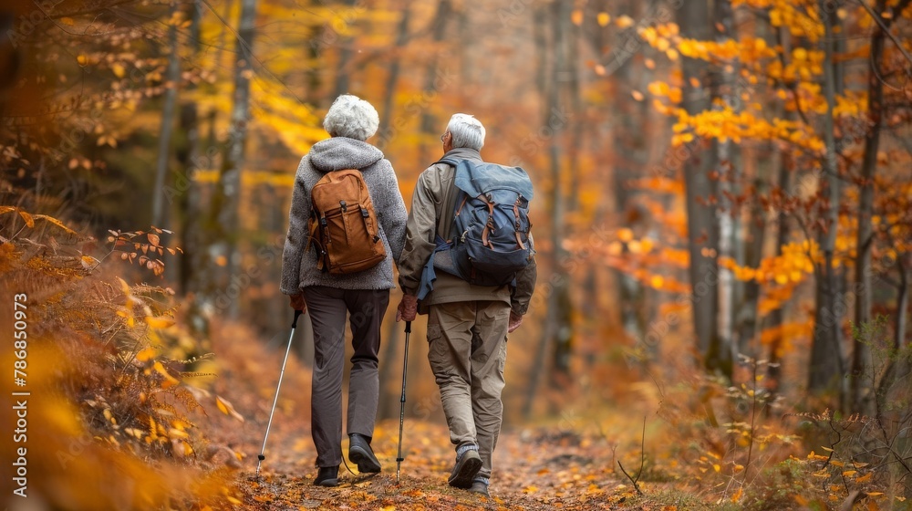 Elderly couple hiking through a forest trail, enjoying the autumn colors