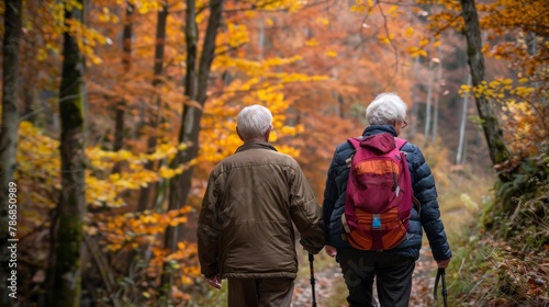 Elderly couple hiking through a forest trail, enjoying the autumn colors © Sasint